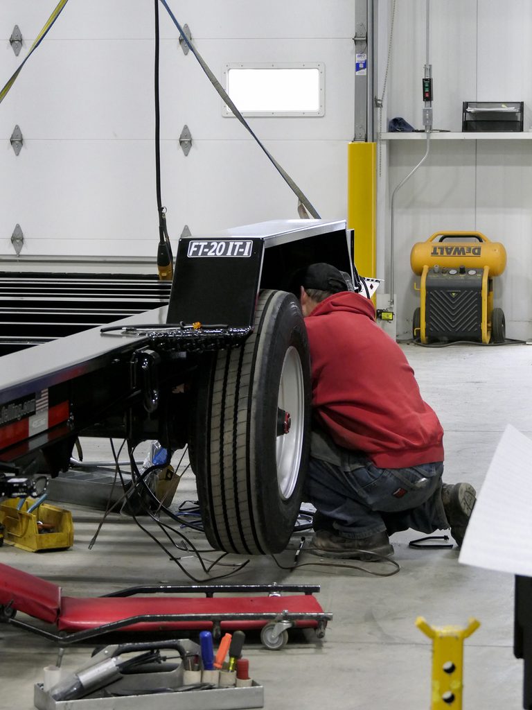 Man in red sweater working on a wheel well of FT-20 IT-I trailer. 