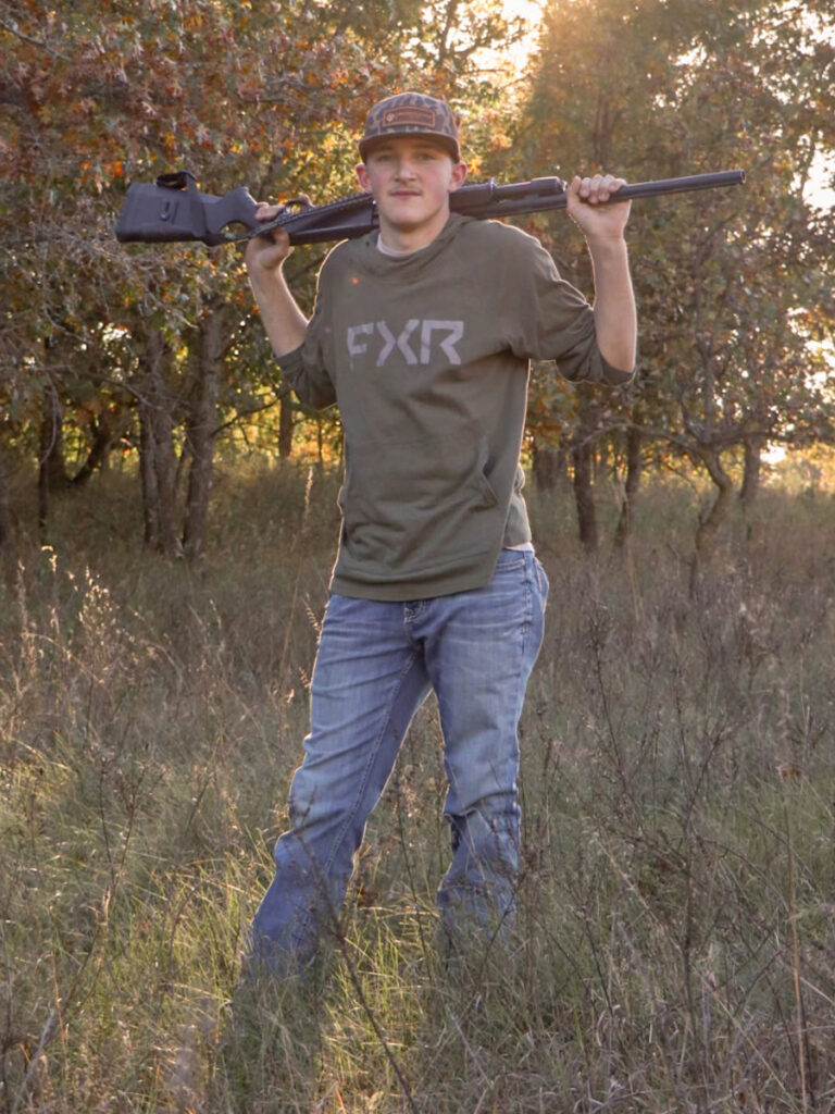 2026 Seton Home Study School graduate Aiden Matt standing outdoors in a wooded field during hunting season.