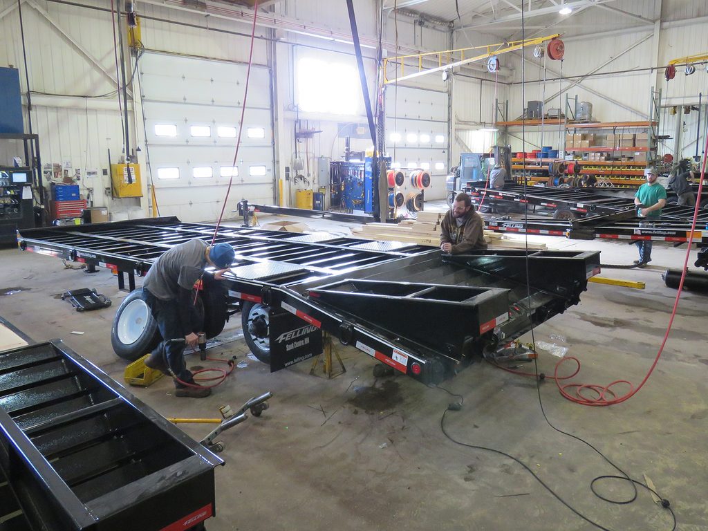 Two men working in a warehouse, assembling trailer. 